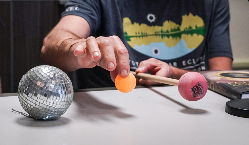a professor holds up three spheres in a line